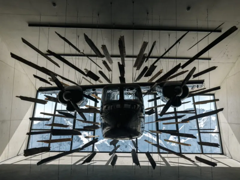 Das Flugzeug aus dem Film Spectre schwebt in 007 Elements vor der Fensterfront, dahinter verschneite Gipfel