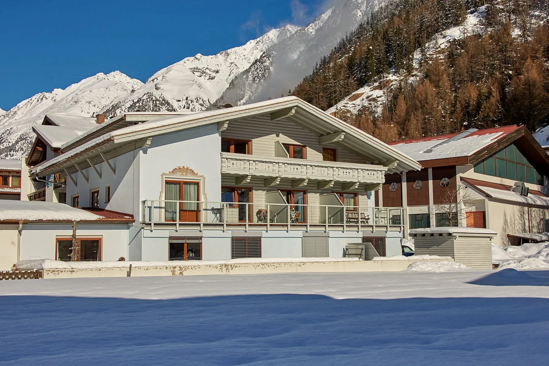 Das Haus Kristiania im Winter von der Strasse aus, dahinter der verschneite Hang