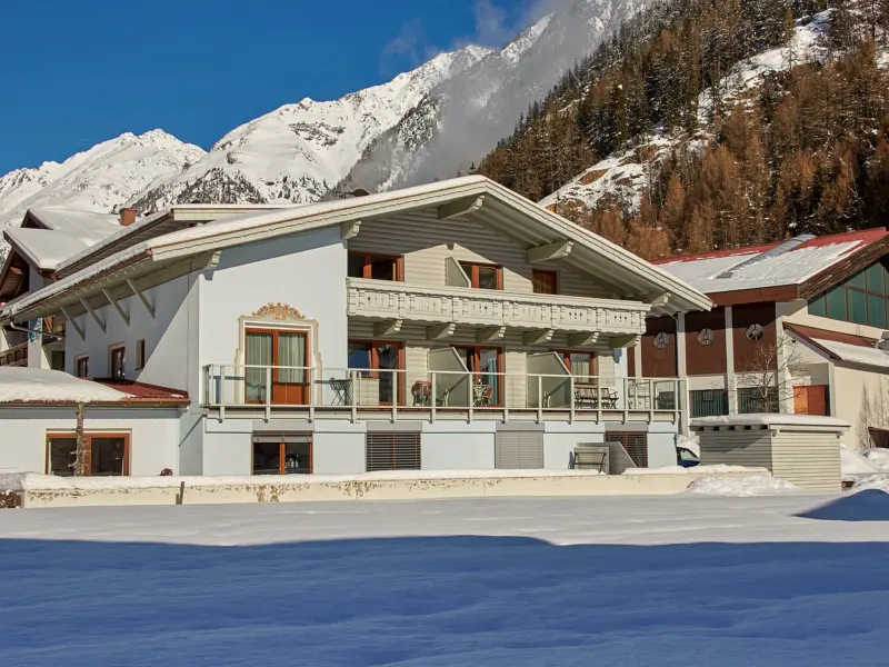 Das Haus Kristiania im Winter von der Strasse aus, dahinter der verschneite Hang
