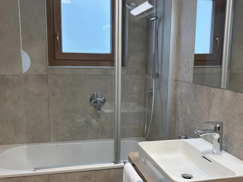 Bad mit Badewanne, Duschwand und Waschtisch im Appartement Nederkogel
